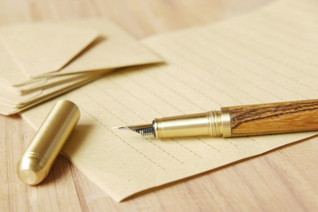 gold and wooden fountain pen on brown envelope