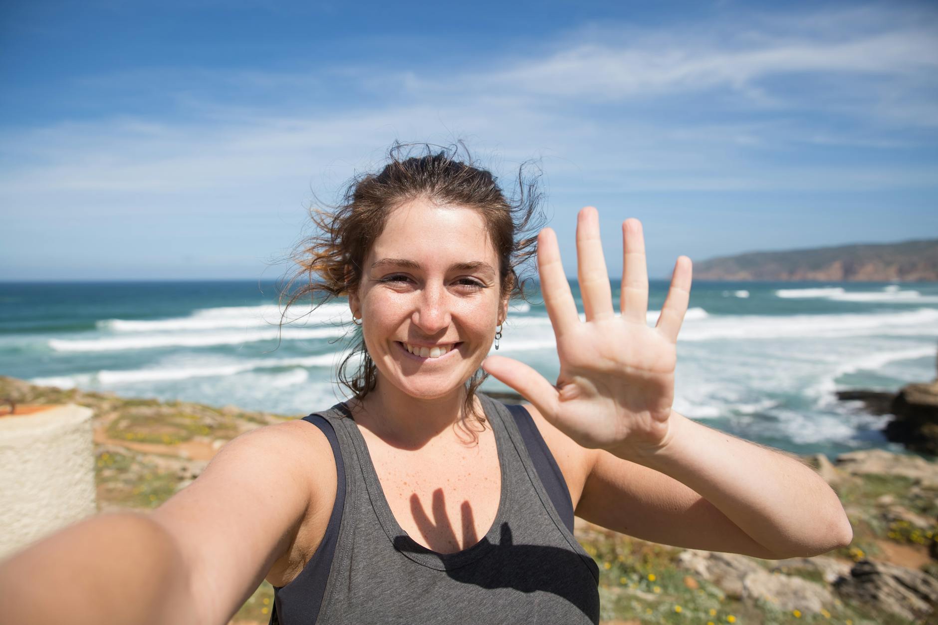 woman in black tank top smiling while showing palm
