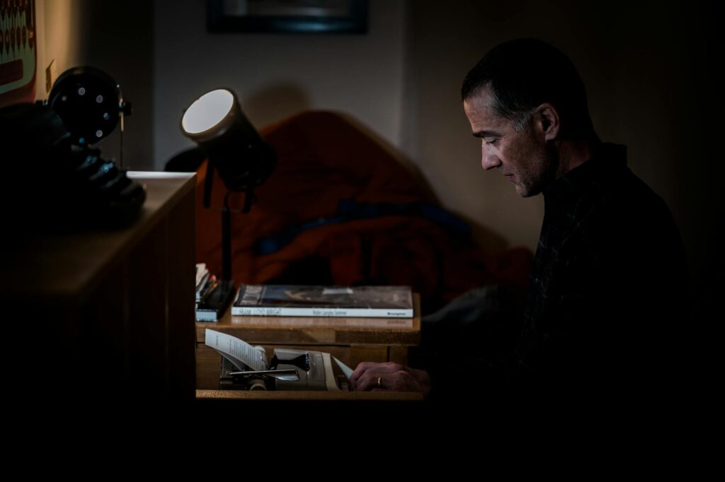man in black shirt typing on a typewriter