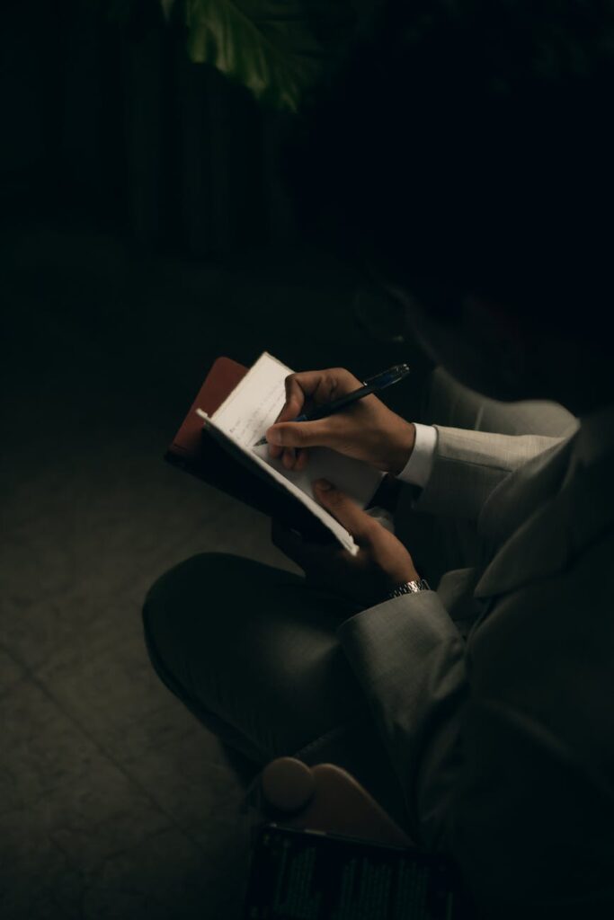 person writing in notebook under low light